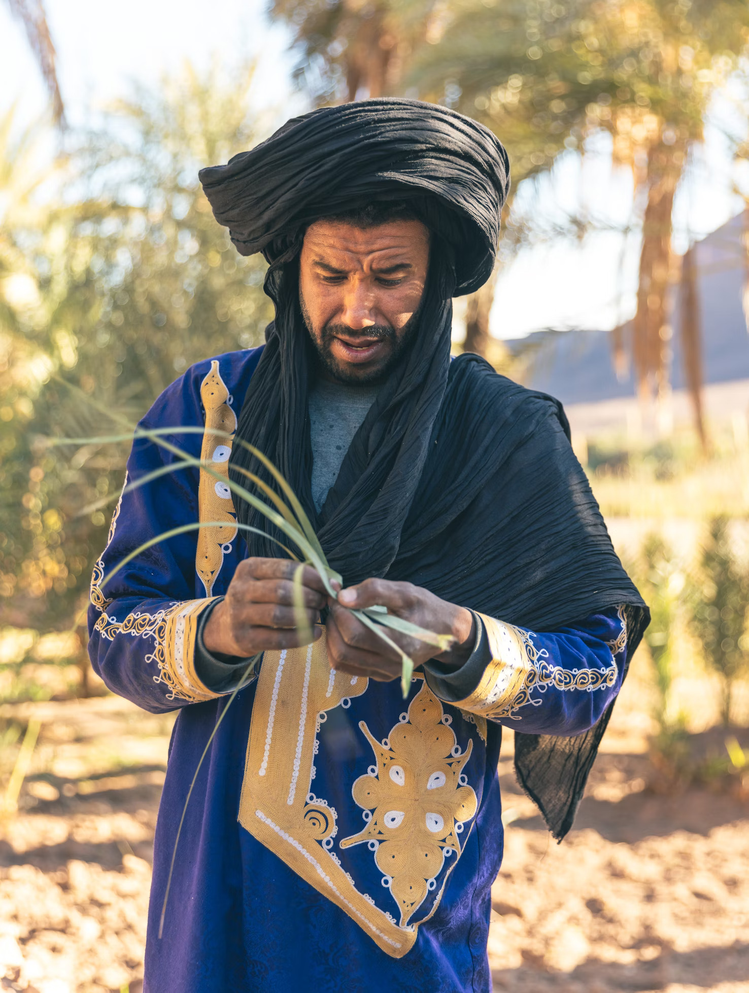 man in wide, black turban 
                                wearing blue tunic with gold patter