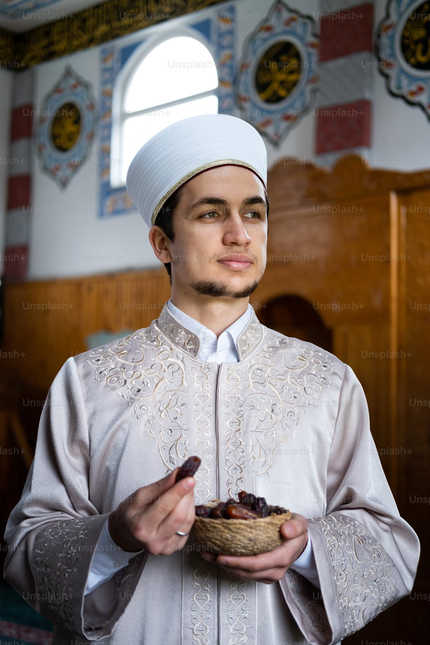 man dressed smartly in silver 
                                    embroidered traditional garb and hat